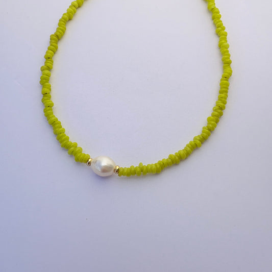 Necklace with green beads and a pearl on a light gray background